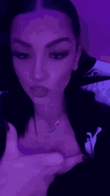 a woman wearing a necklace with an evil eye on it is giving the middle finger .