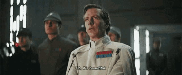 a man in a white uniform is standing in front of a group of men and saying oh it 's beautiful .