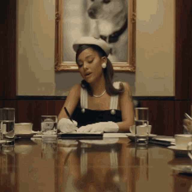a woman sits at a table with a pen in her hand