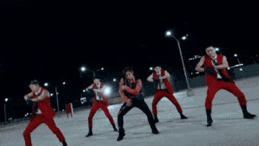 a group of men in red are dancing in front of a lightning strike