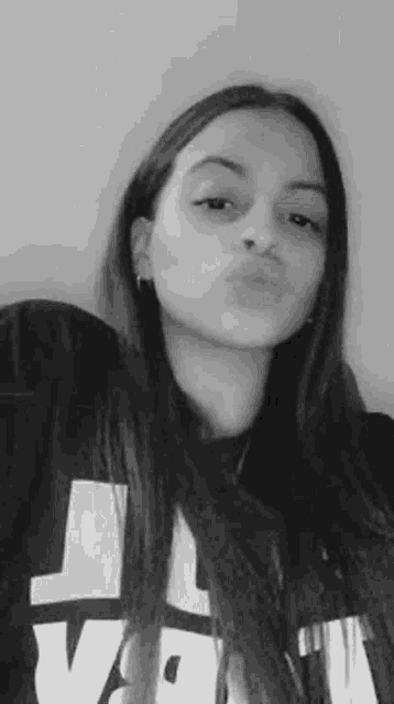 a young woman is blowing a kiss in a black and white photo .