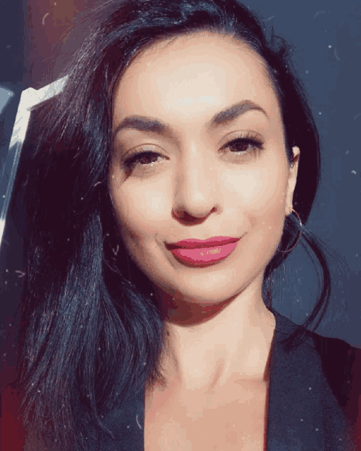 a woman with long dark hair and pink lipstick smiles for the camera