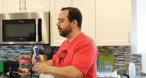 a man in a red shirt that says s7 is standing in a kitchen