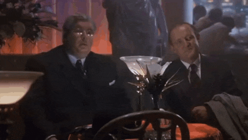 a man in a suit and tie is clapping while sitting at a table .