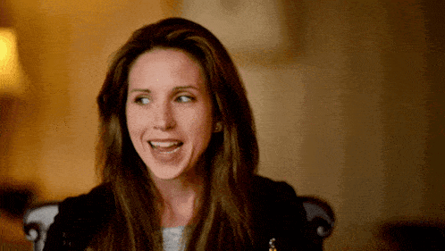 a woman with long brown hair is smiling and looking away from the camera