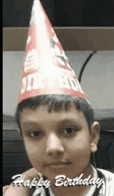 a young boy wearing a birthday hat with the words happy birthday written on it