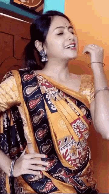 a woman wearing a yellow and black saree is singing