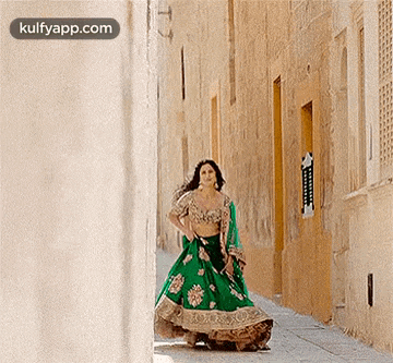 a woman in a green dress is walking down a sidewalk .