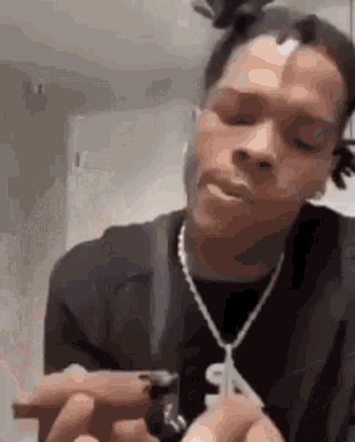 a man with dreadlocks is smoking a cigarette in a room .