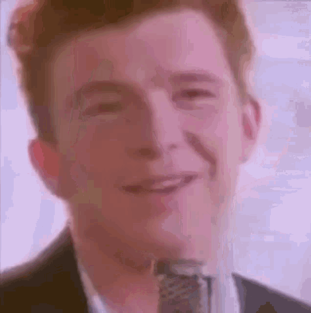 rick roll is smiling while singing into a microphone in a video .