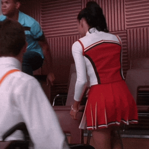 a cheerleader in a red and white uniform is standing in front of a man in a wheelchair