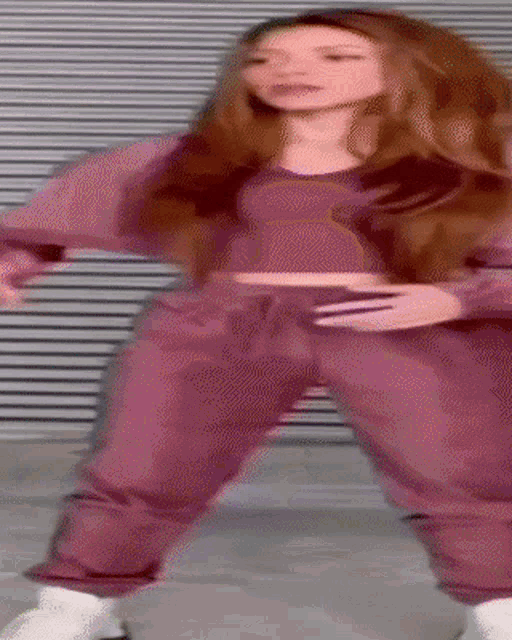 a woman in a crop top and purple sweatpants is dancing