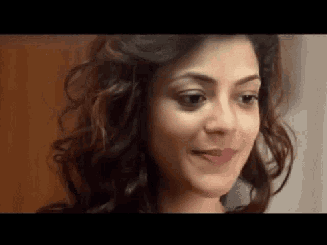 a close up of a woman 's face with curly hair smiling .