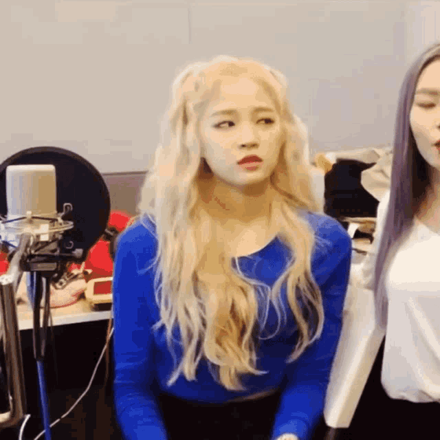 a blonde woman in a blue shirt is sitting next to another blonde woman