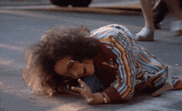 a woman with curly hair is laying on the ground with her mouth open