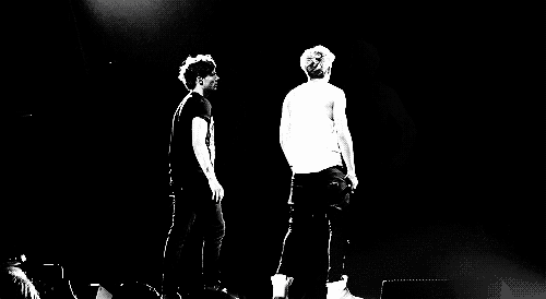 two men are standing on a stage with microphones in their hands .