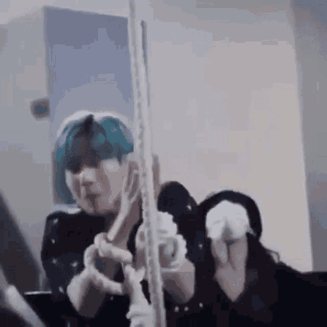 a man with blue hair is standing in front of a mirror and looking at himself .