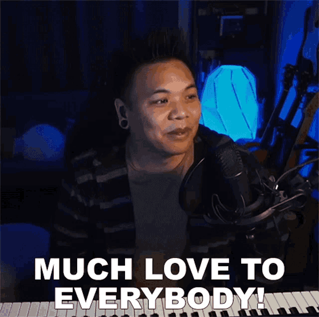 a man singing into a microphone with the words much love to everybody behind him
