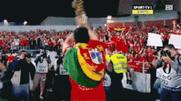 a soccer player holds up a trophy in front of a crowd with a sign that says sport tv