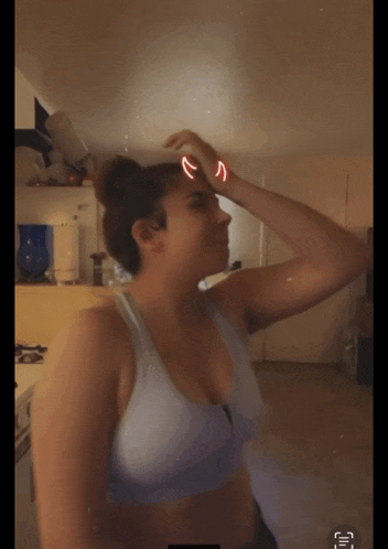 a woman in a sports bra is standing in a kitchen