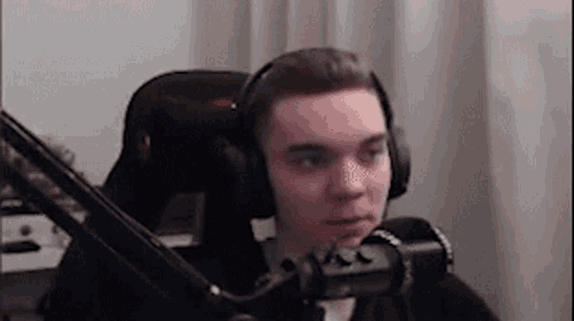 a young man wearing headphones is sitting in front of a microphone in a chair .