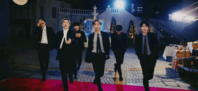 a group of men in suits and ties are walking on a red carpet in front of a sign that says sweettones