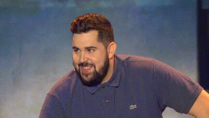 a man with a beard is wearing a blue shirt with a lacoste logo on it .