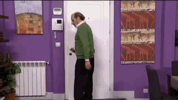 a man in a green sweater is standing in front of a white door