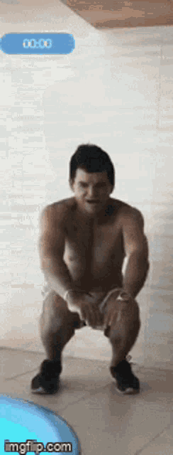 a shirtless man squatting in front of a blue button that says 00:00 on it