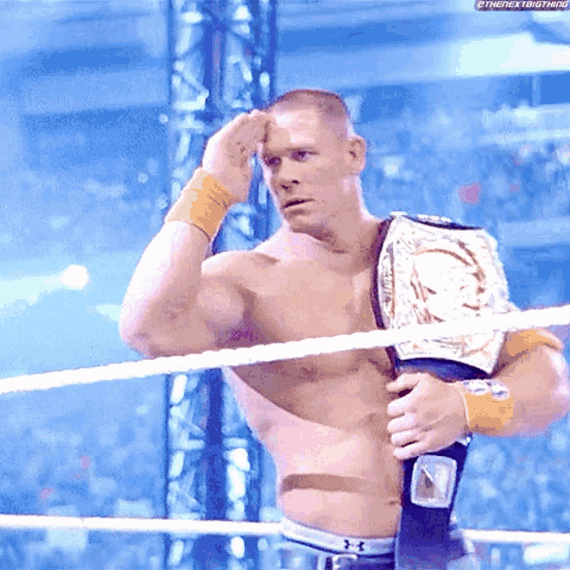 a shirtless wrestler wearing a championship belt is standing in a ring