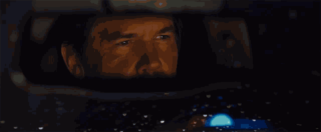 a man in a car looking at the rear view mirror