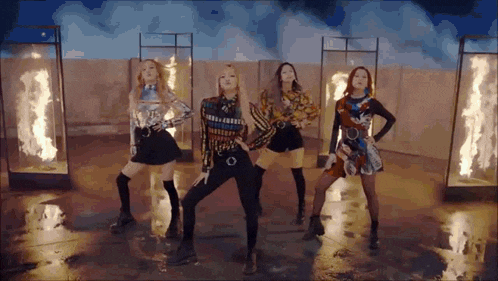a group of girls are standing next to each other on a stage in front of fire .
