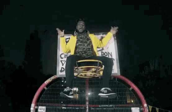 a man in a yellow jacket is riding a ferris wheel at night .
