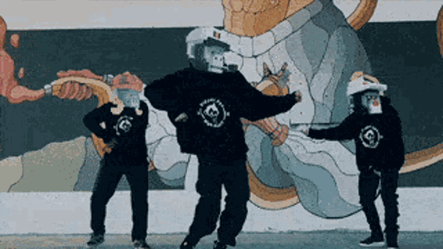 a group of people wearing monkey masks are dancing in front of a mural on a wall