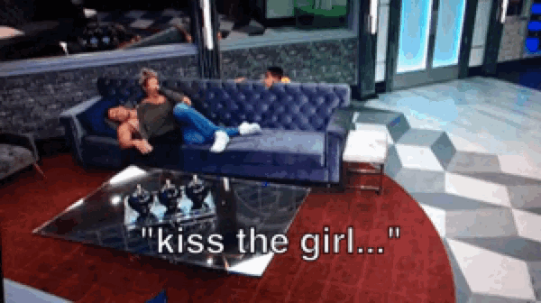a couple laying on a couch with the words " kiss the girl " on the screen
