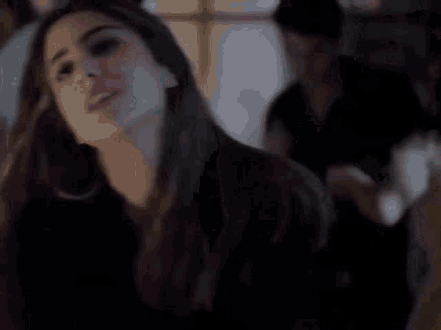 a woman is dancing in a dark room with a group of people behind her .