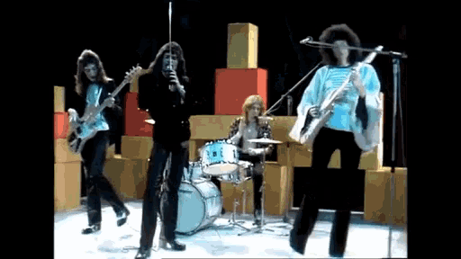 a group of people are playing instruments and singing into microphones on a stage .