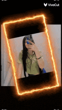 a girl is taking a picture of herself in a mirror with a fire frame around her .
