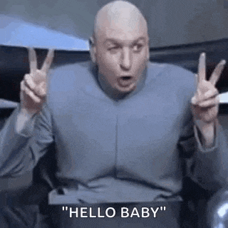 a bald man is making a peace sign with his hands while sitting in a chair .