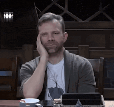 a man sitting at a table with his hand on his head