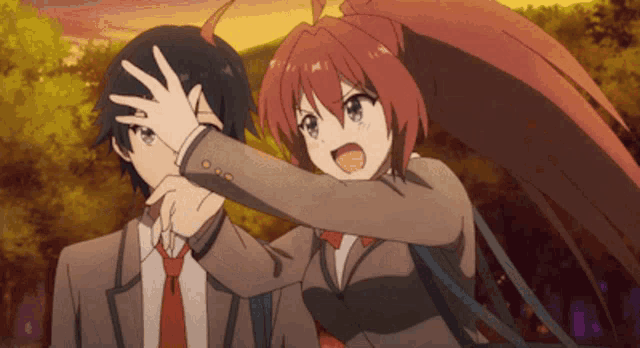 a boy and a girl are standing next to each other and the girl is covering the boy 's face with her hands