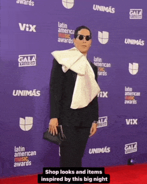 a man stands on a purple carpet with latin american music awards written on it