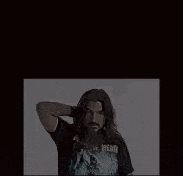a man with long hair and a beard is wearing a t-shirt that says " the head " on it