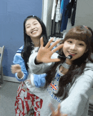 two girls are posing for a picture and one has a sweatshirt that says england on it