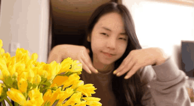 a woman is sitting in front of a vase of yellow flowers .