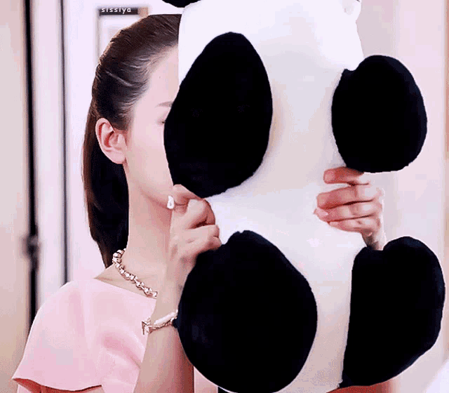 a woman covering her face with a stuffed panda