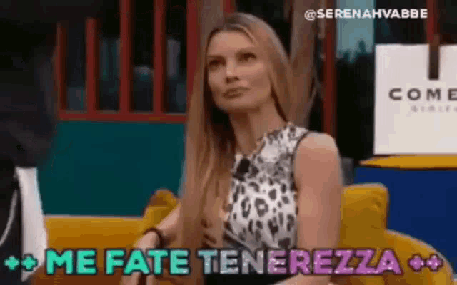 a woman is sitting on a yellow couch with the words `` me fate tenerezza '' written on her face .