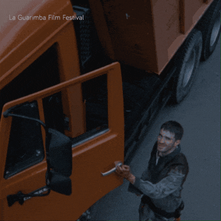 a man is standing next to an orange truck with the words la guarimba film festival written on the bottom