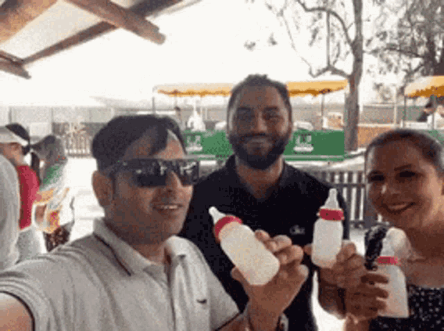 a man and two women are holding baby bottles and smiling for the camera