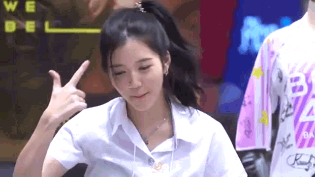 a girl in a white shirt is giving the peace sign